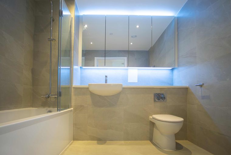 A modern bathroom with a bathtub, shower, sink, and toilet.