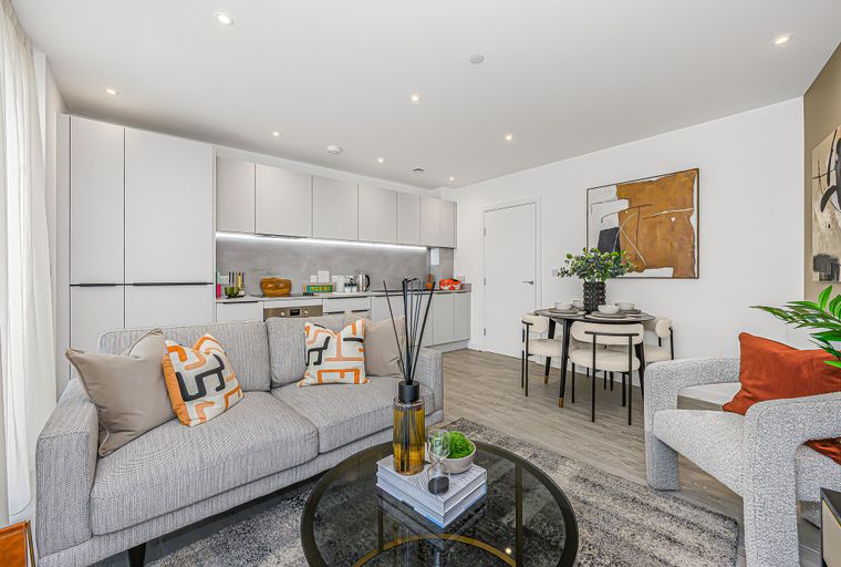 A living room and kitchen area with a sofa, dining table, and modern cabinets.