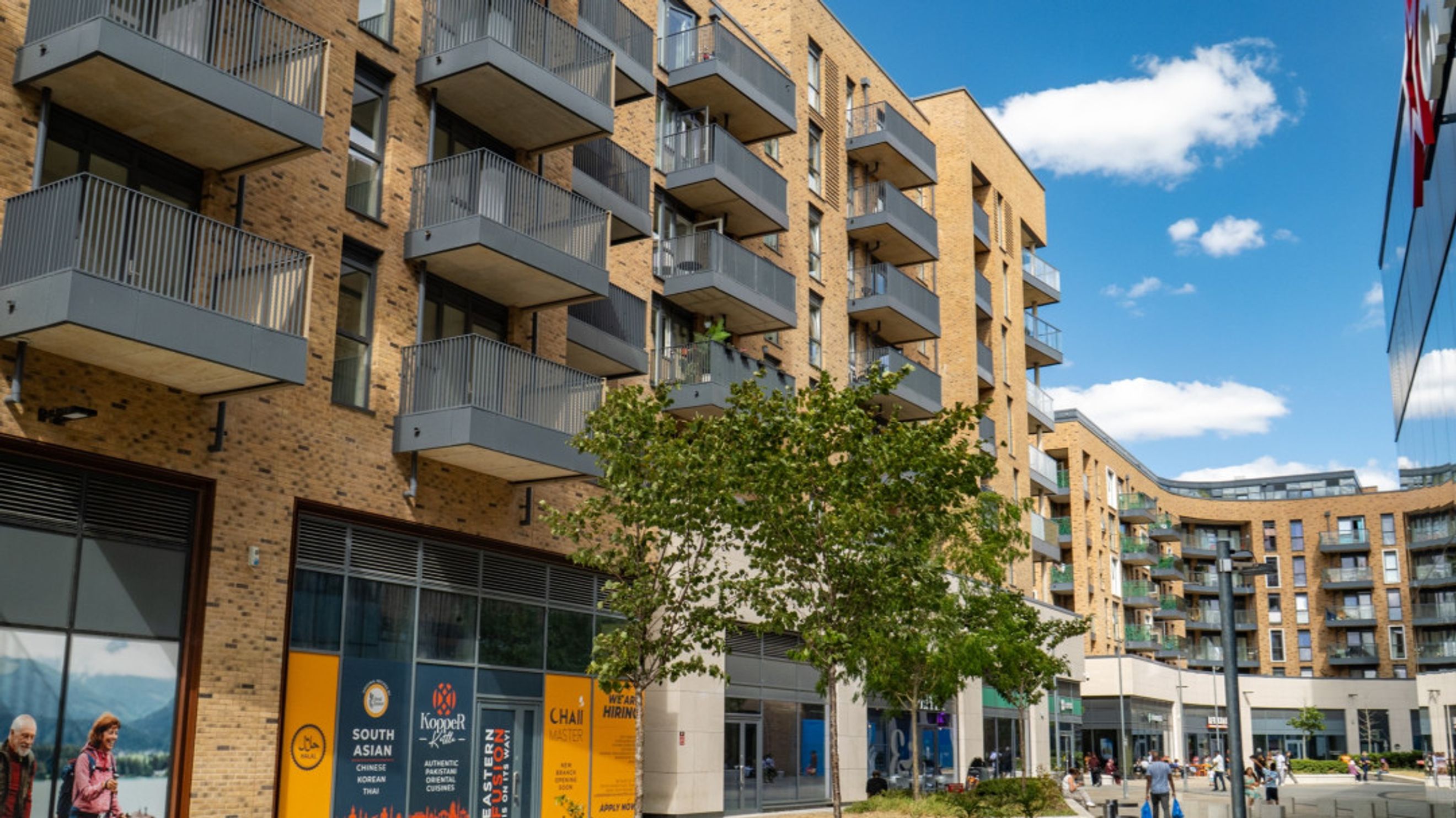 A modern apartment building with balconies and ground-floor shops.