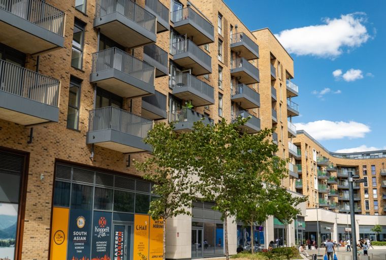 A modern apartment building with balconies and ground-floor shops.
