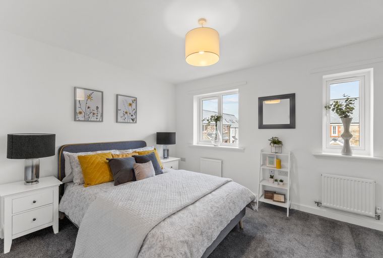 A bedroom with a bed, bedside tables, and windows.
