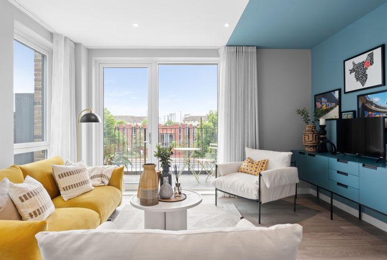 A living room with a yellow sofa, a white armchair, a coffee table, and a blue media console with a television.
