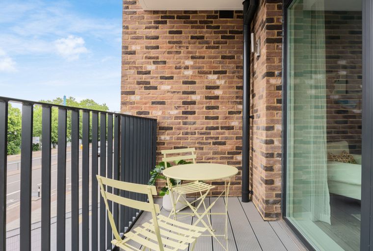 A balcony with a table and two chairs overlooking a street.
