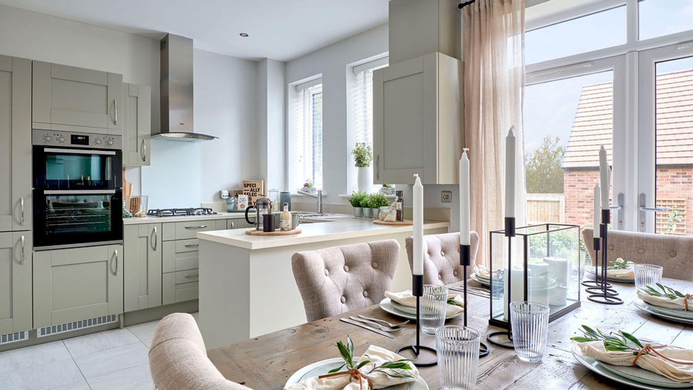 A kitchen and dining area with grey cabinets, an island, and a dining table set for a meal.