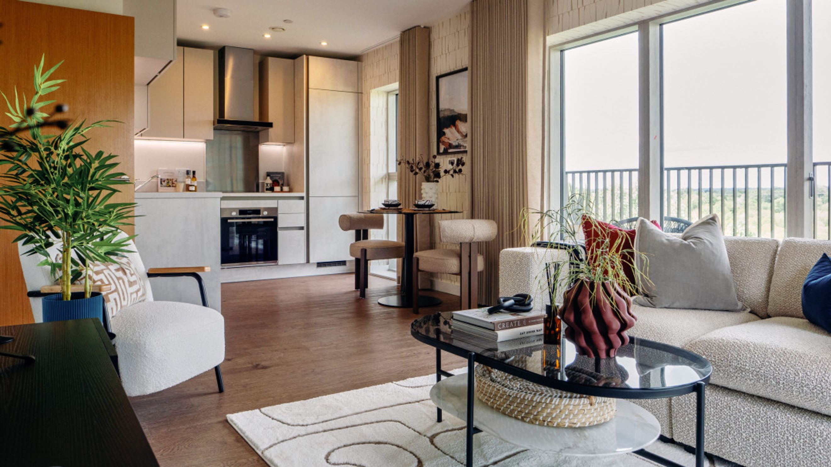 A living room and kitchen area with a sofa, coffee table, dining table, and kitchen cabinets.