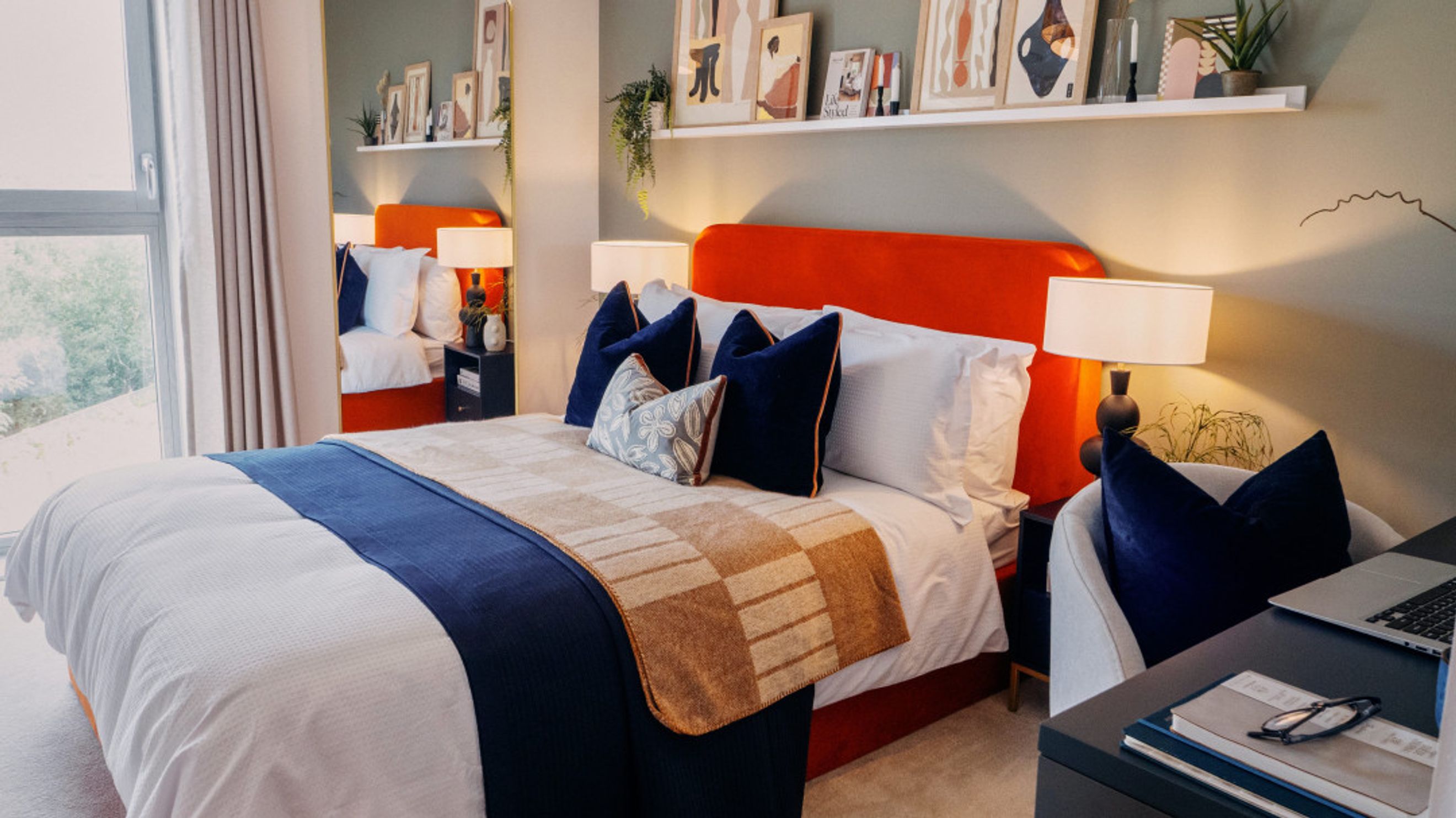 A bedroom with a bed, pillows, and a desk.