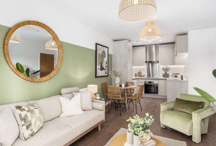 A living room and kitchen area with a sofa, dining table, chairs, and kitchen cabinets.