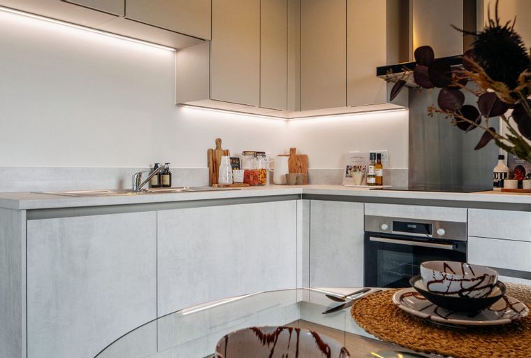 A modern kitchen with light grey cabinets, a sink, and an oven.