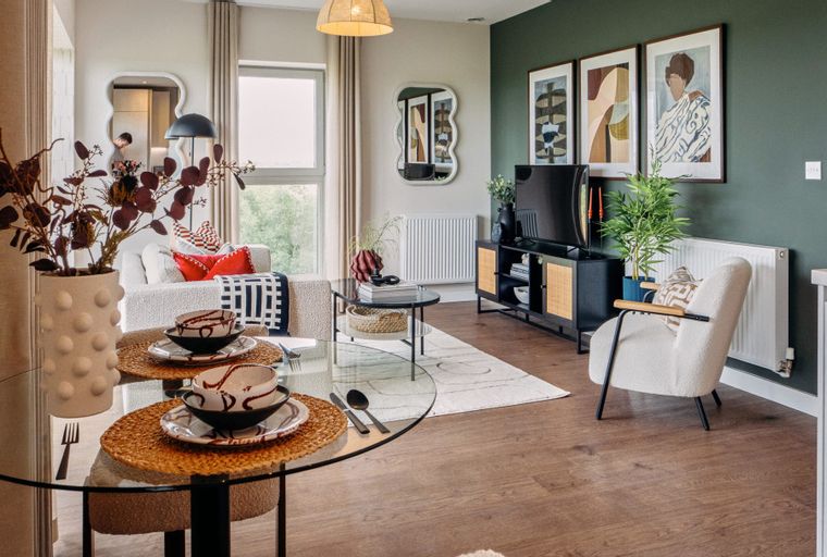 A dining and living room area with a glass dining table, sofa, and television.