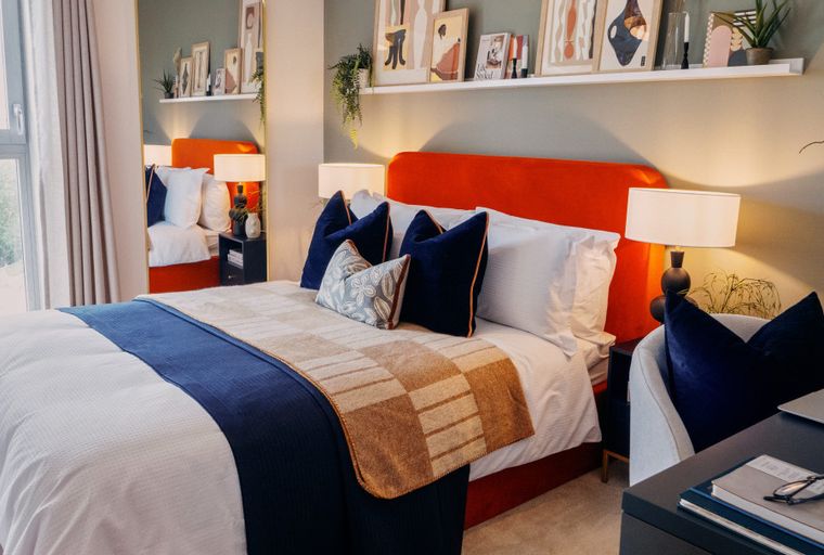 A bedroom with a bed, pillows, and a desk.