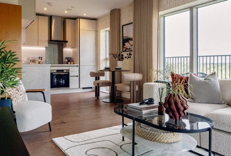 A living room and kitchen area with a sofa, coffee table, dining table, and kitchen cabinets.