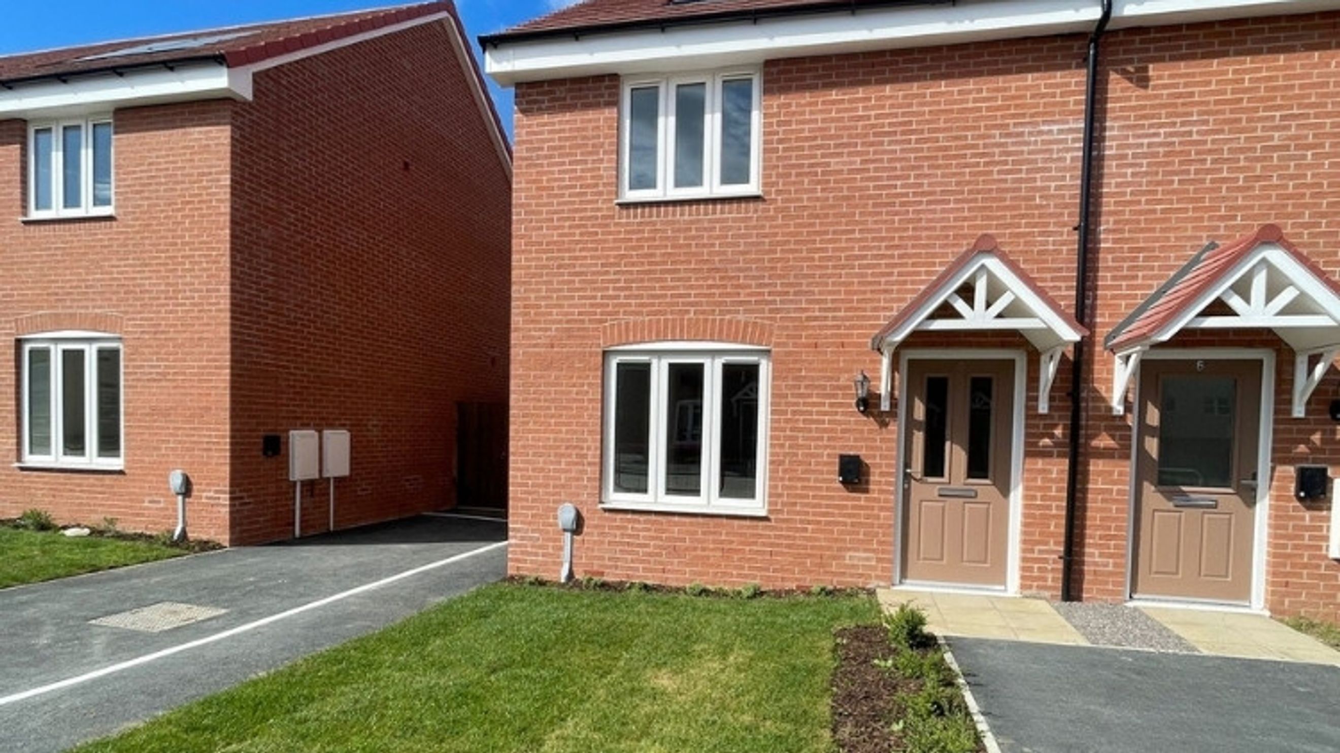 A row of newly built brick townhouses with white windows and front doors.