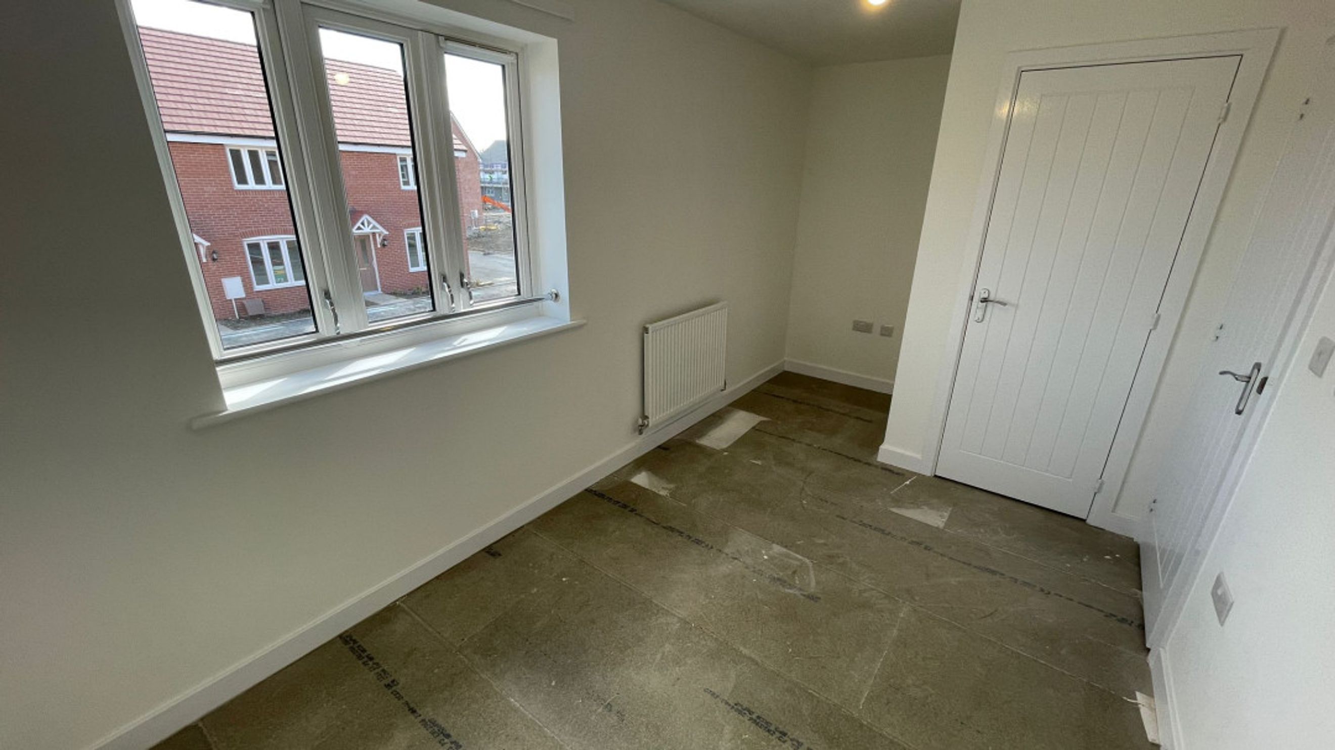 A room with a window, radiator, and a door.