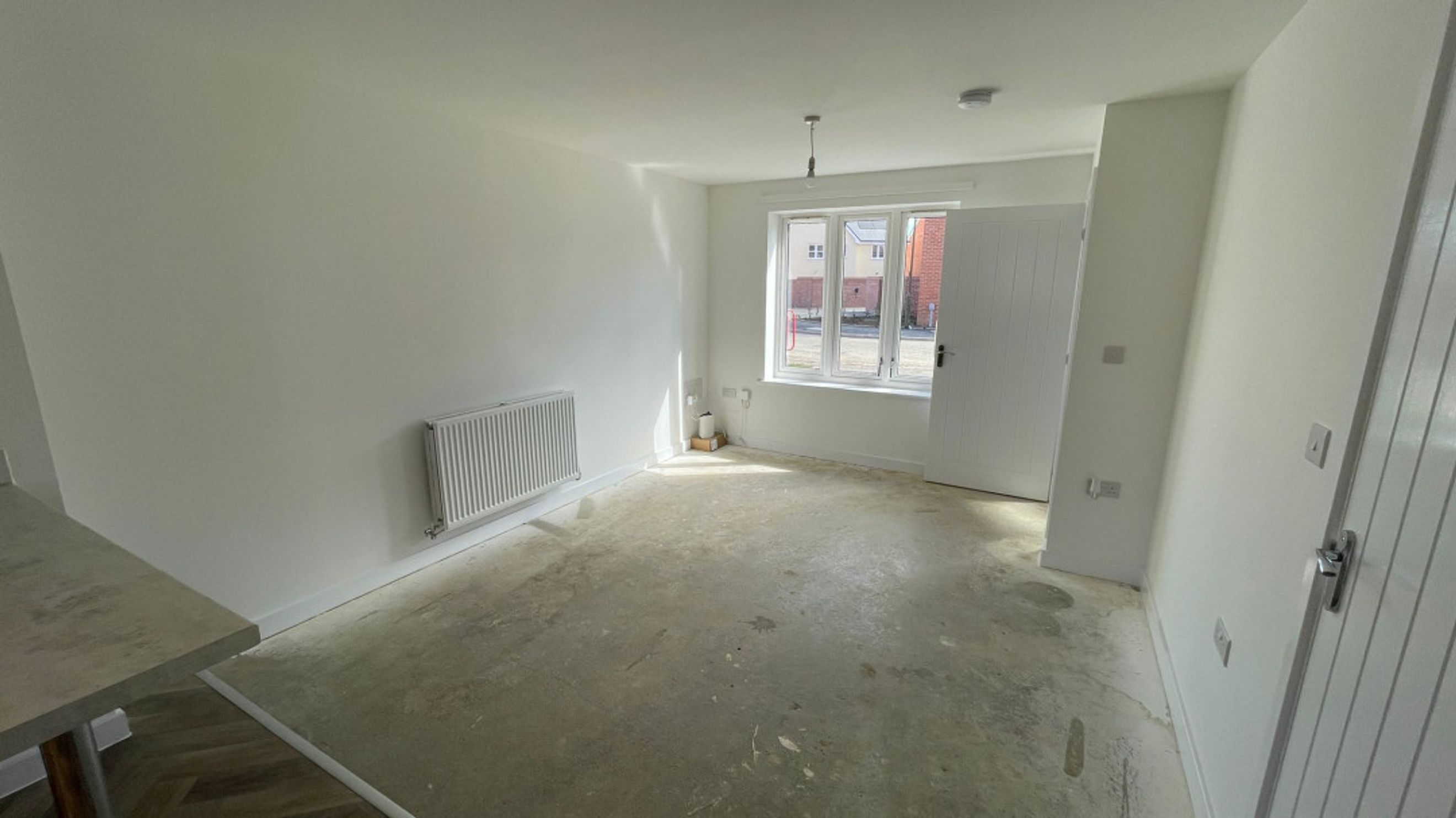 A room with a window, radiator, and a door.