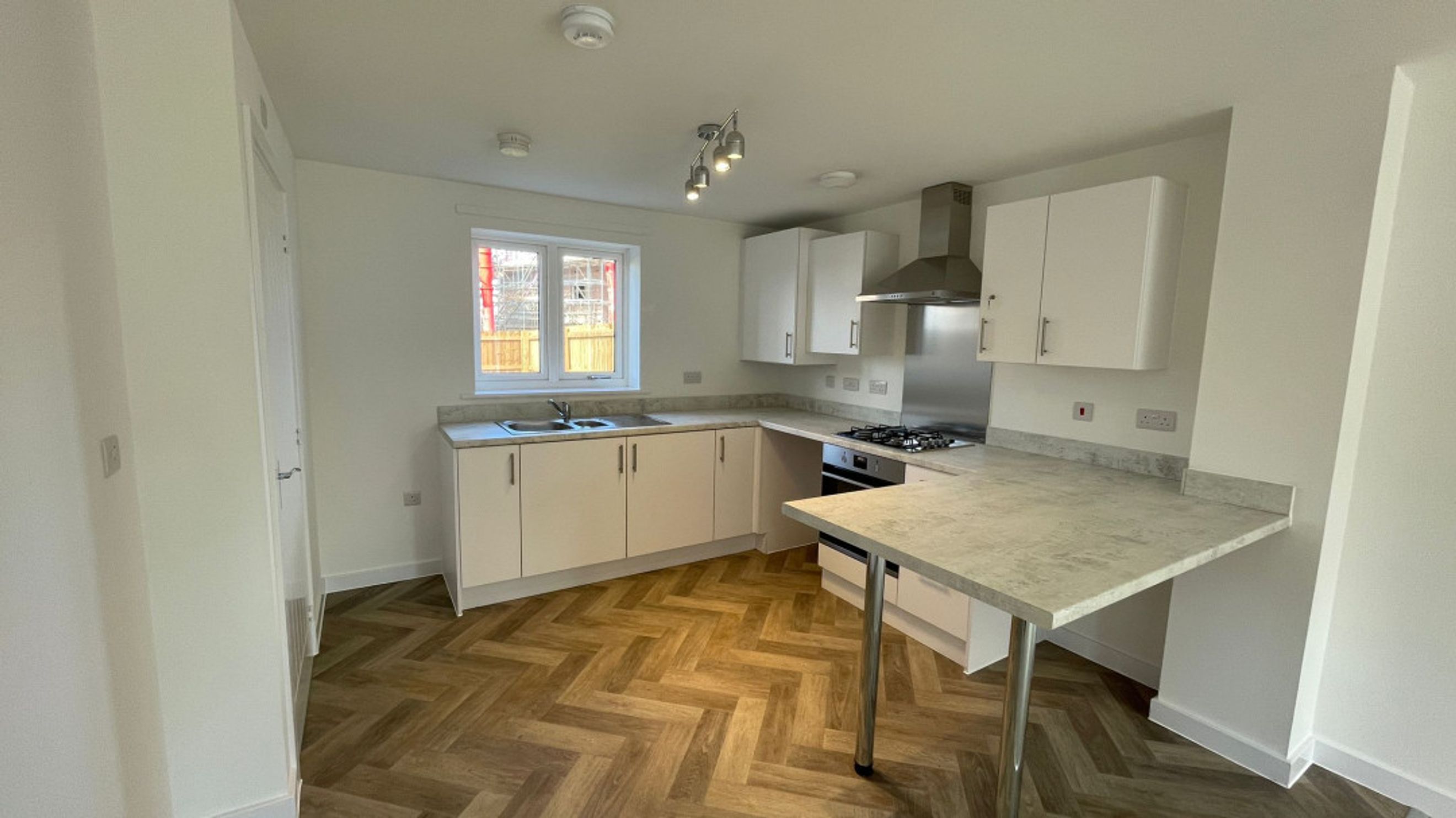 A modern kitchen with white cabinets, a sink, a stove, and a breakfast bar.