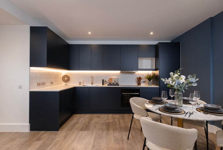 A modern kitchen and dining area with dark cabinets, a marble-top table, and upholstered chairs.