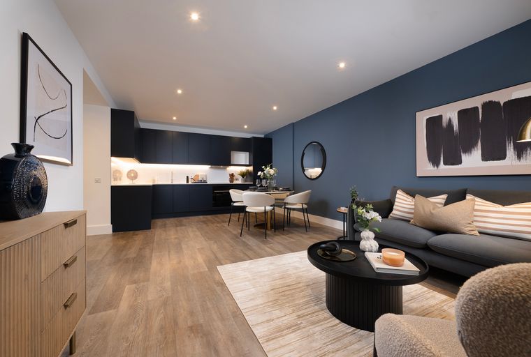 A living room and kitchen area with a sofa, coffee table, dining table, and kitchen cabinets.