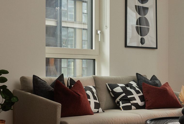 A living room with a sofa, pillows, and a window.