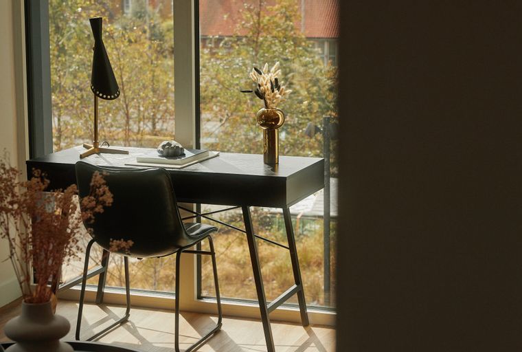 A desk with a chair in front of a window.