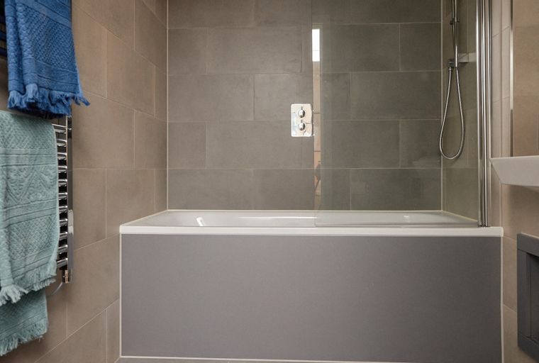 A bathroom with a bathtub, shower, and towels on a heated towel rail.