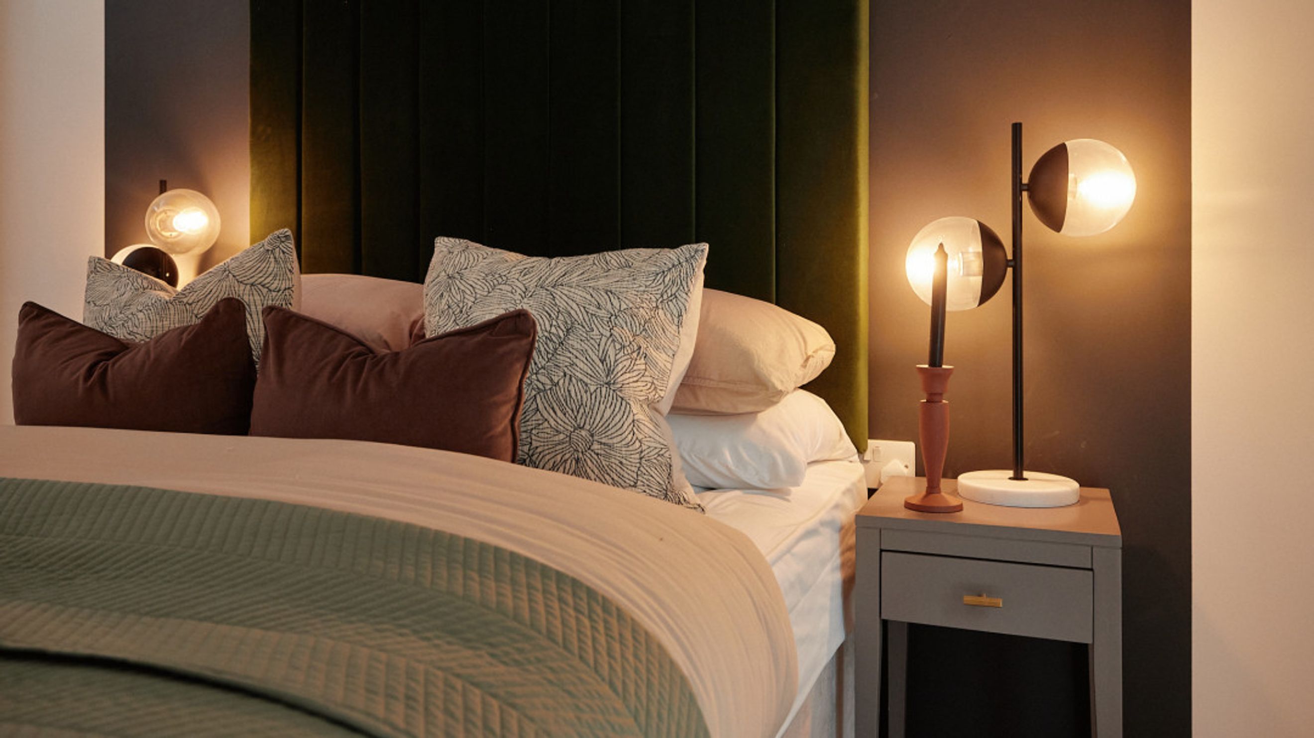 A bedroom with a bed, pillows, and bedside lamps.