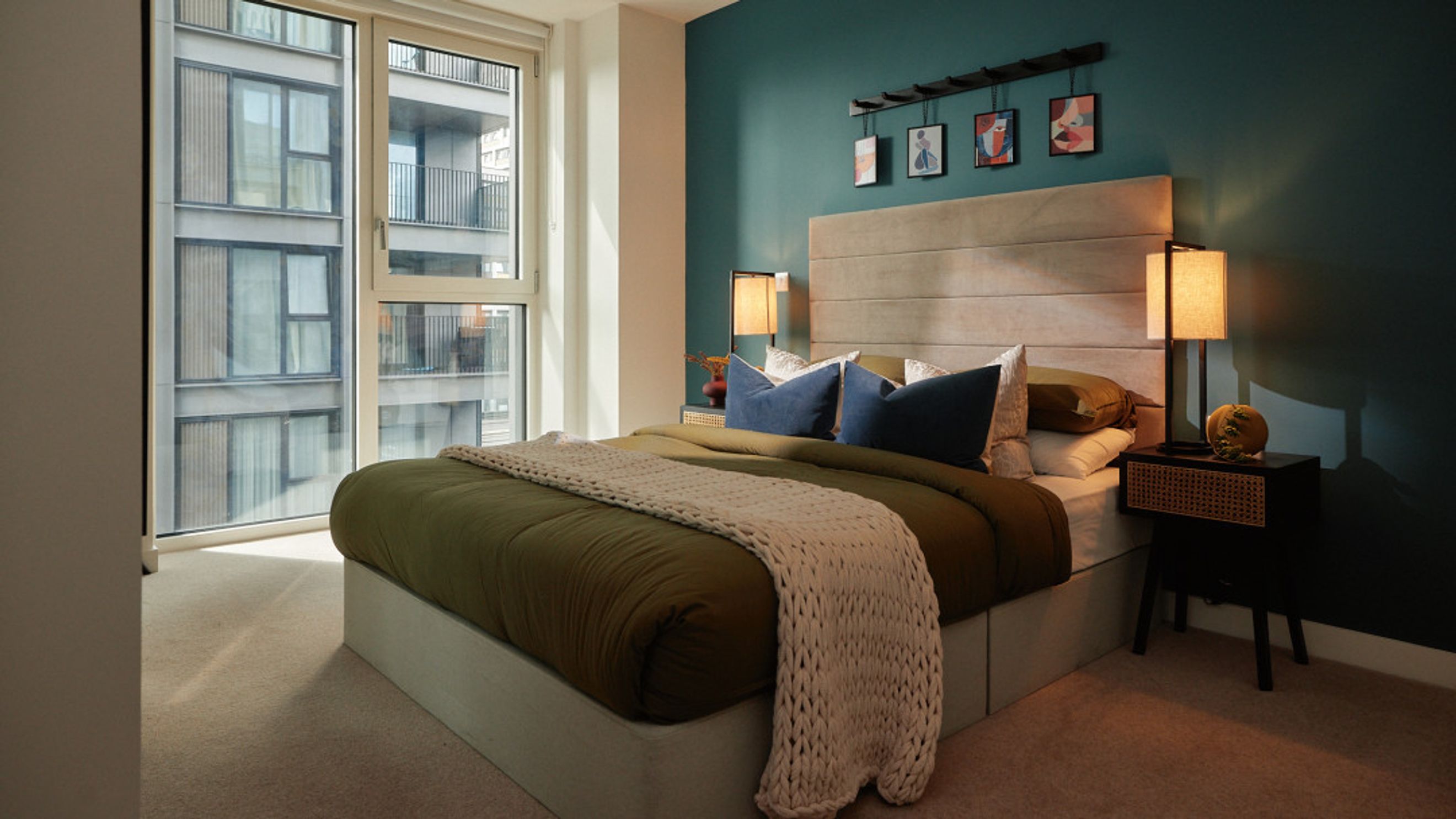 A bedroom with a bed, pillows, a nightstand, and a window.