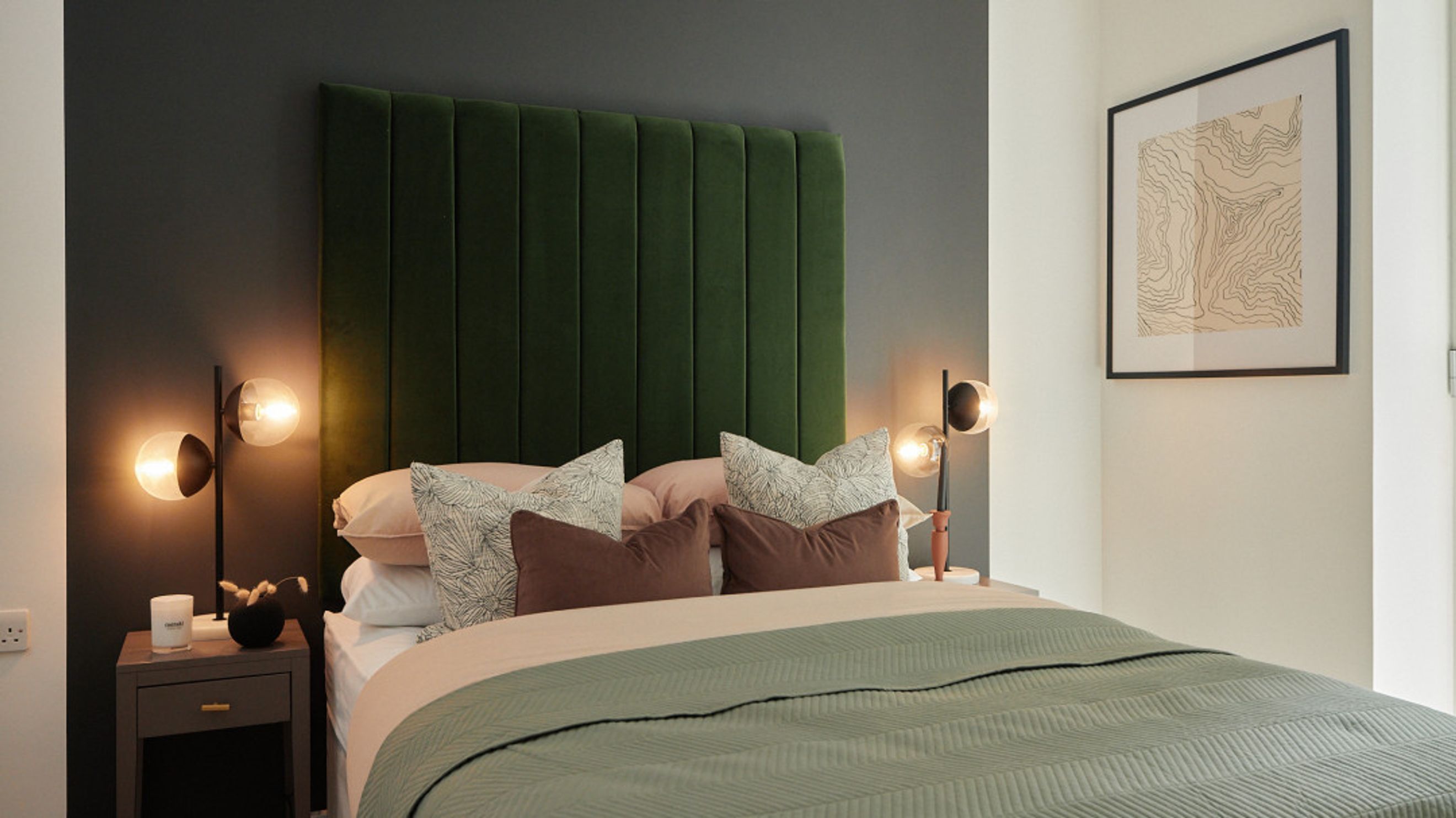 A bedroom with a bed, pillows, a headboard, and a bedside lamp.
