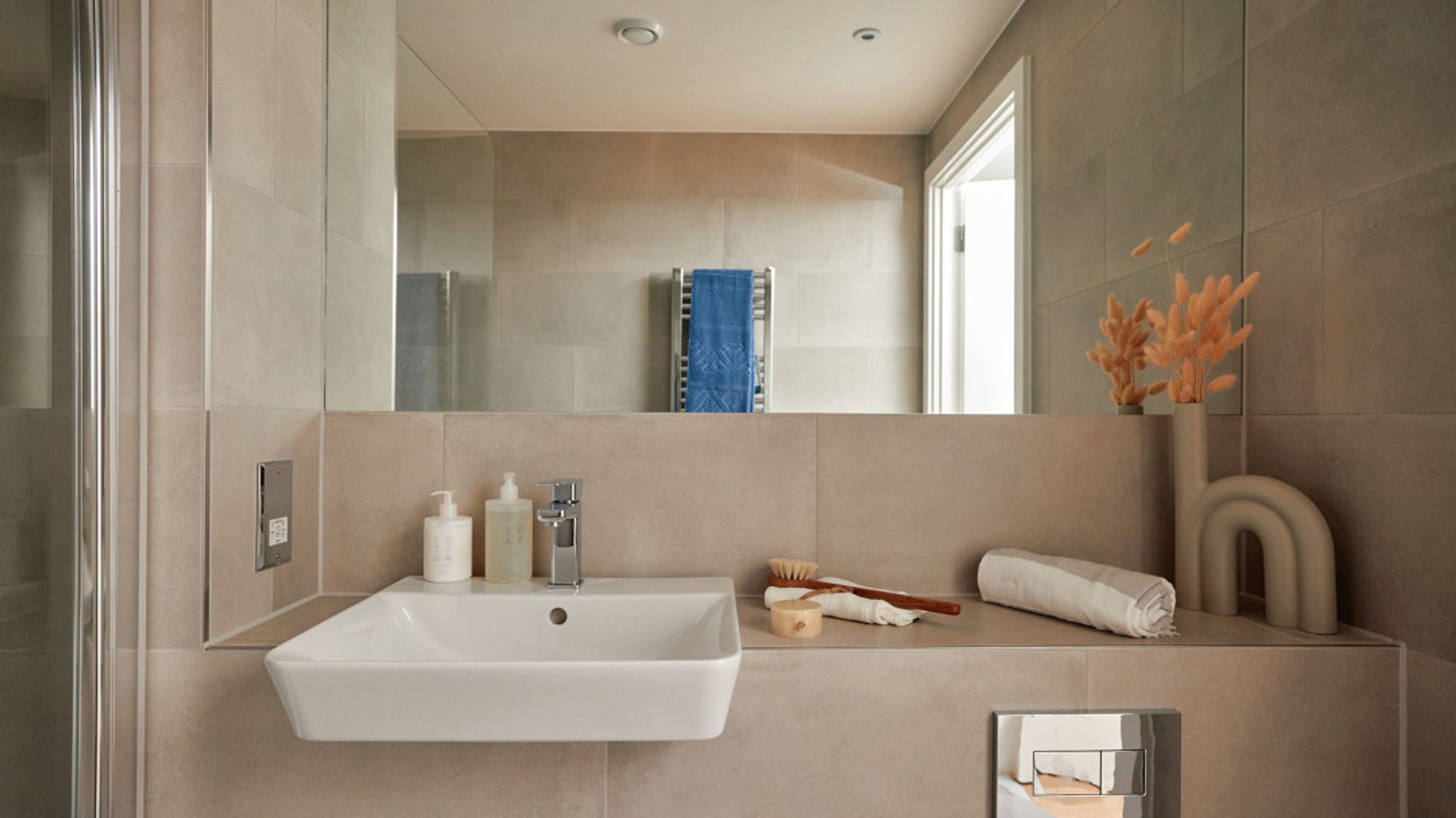 A modern bathroom with a sink, faucet, mirror, and decorative items.