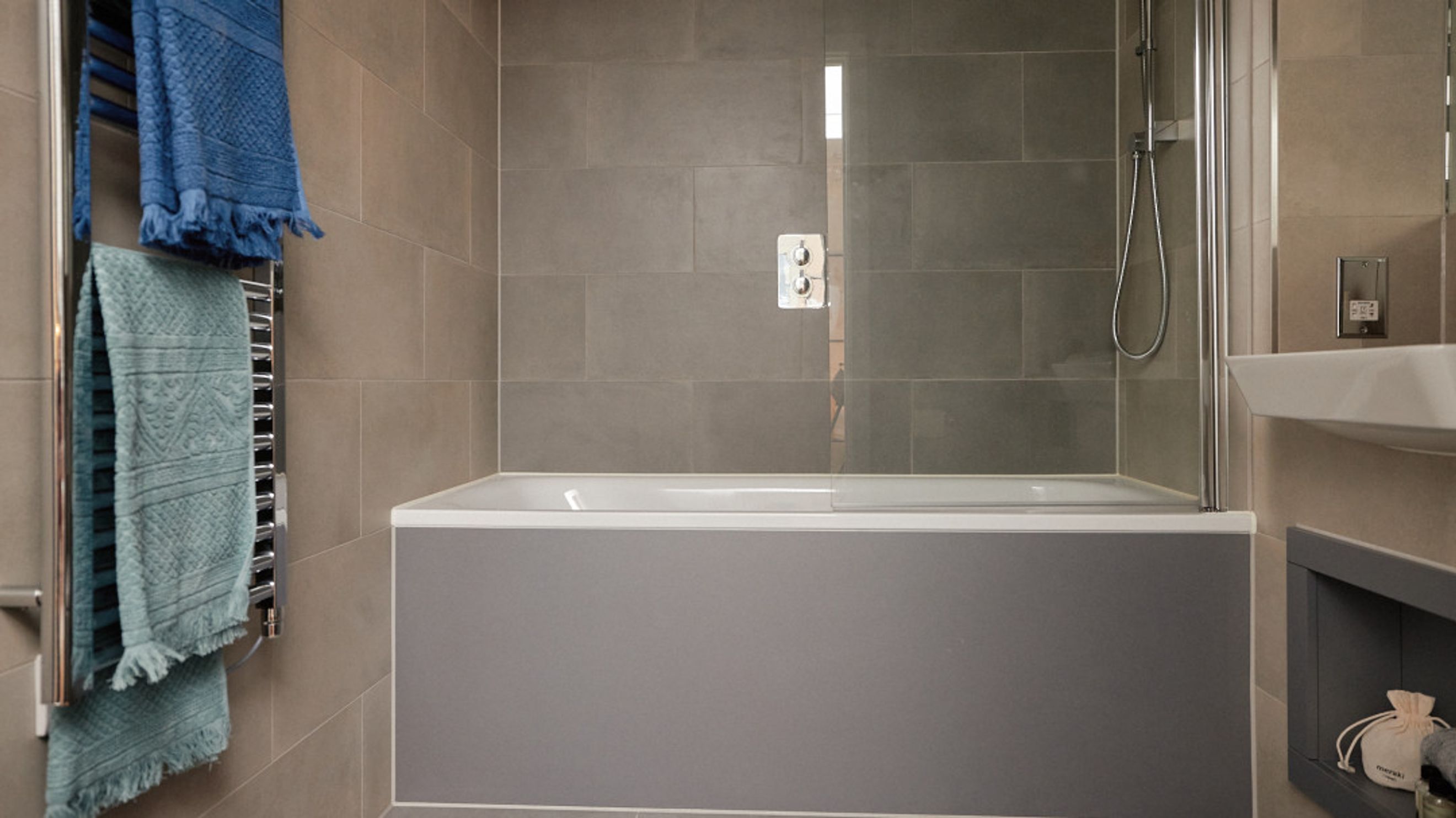 A bathroom with a bathtub, shower, and towels on a heated towel rail.