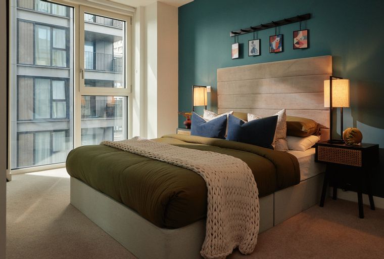 A bedroom with a bed, pillows, a nightstand, and a window.