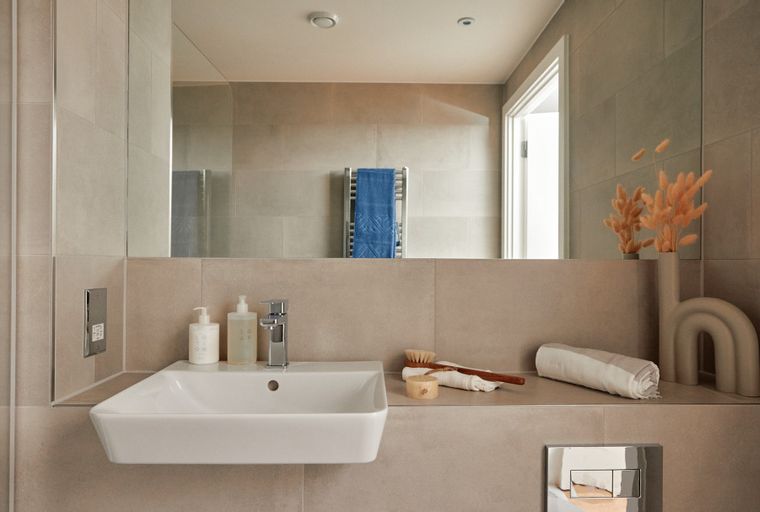 A modern bathroom with a sink, faucet, mirror, and decorative items.