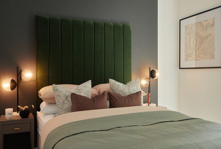A bedroom with a bed, pillows, a headboard, and a bedside lamp.