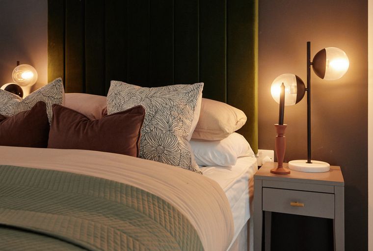 A bedroom with a bed, pillows, and bedside lamps.