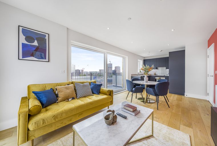 A living room and dining area with a yellow sofa, blue chairs, and a marble coffee table.