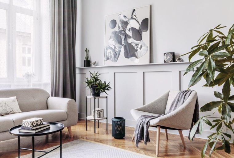 A living room with a sofa, armchair, coffee table, and artwork.