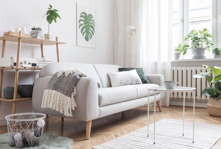 A living room with a sofa, side table, and plants.