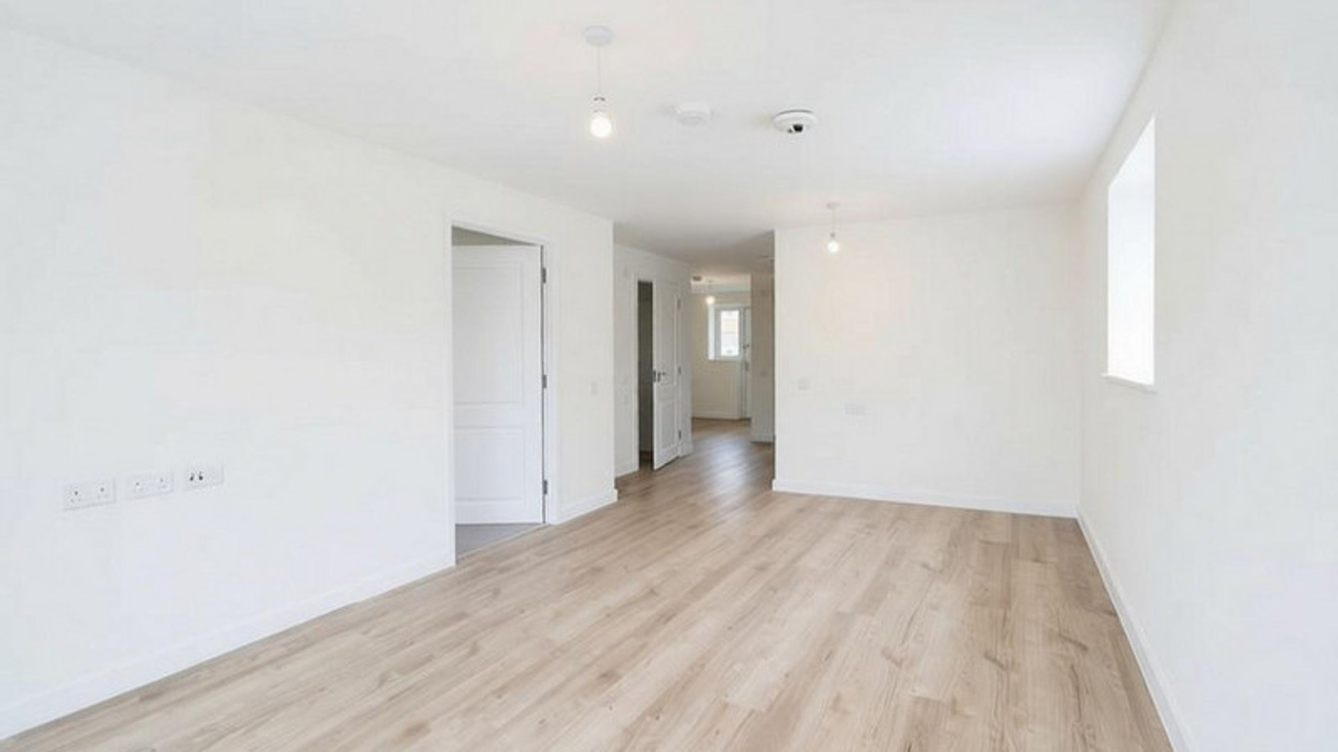 A hallway with multiple doors and a window.
