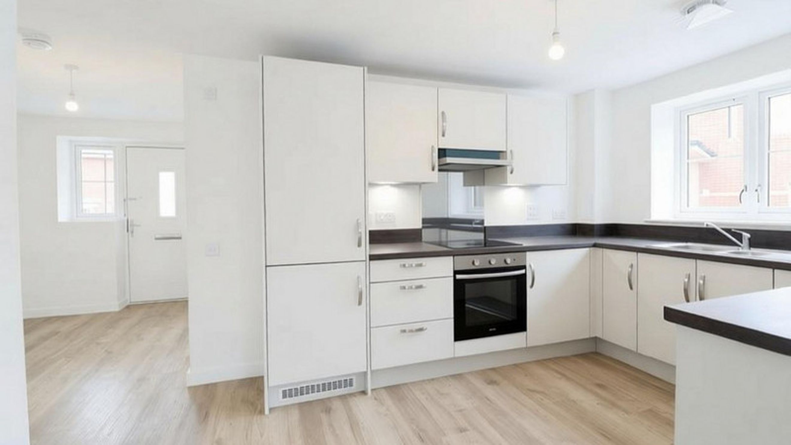 A modern kitchen with white cabinets, a dark countertop, and an oven.
