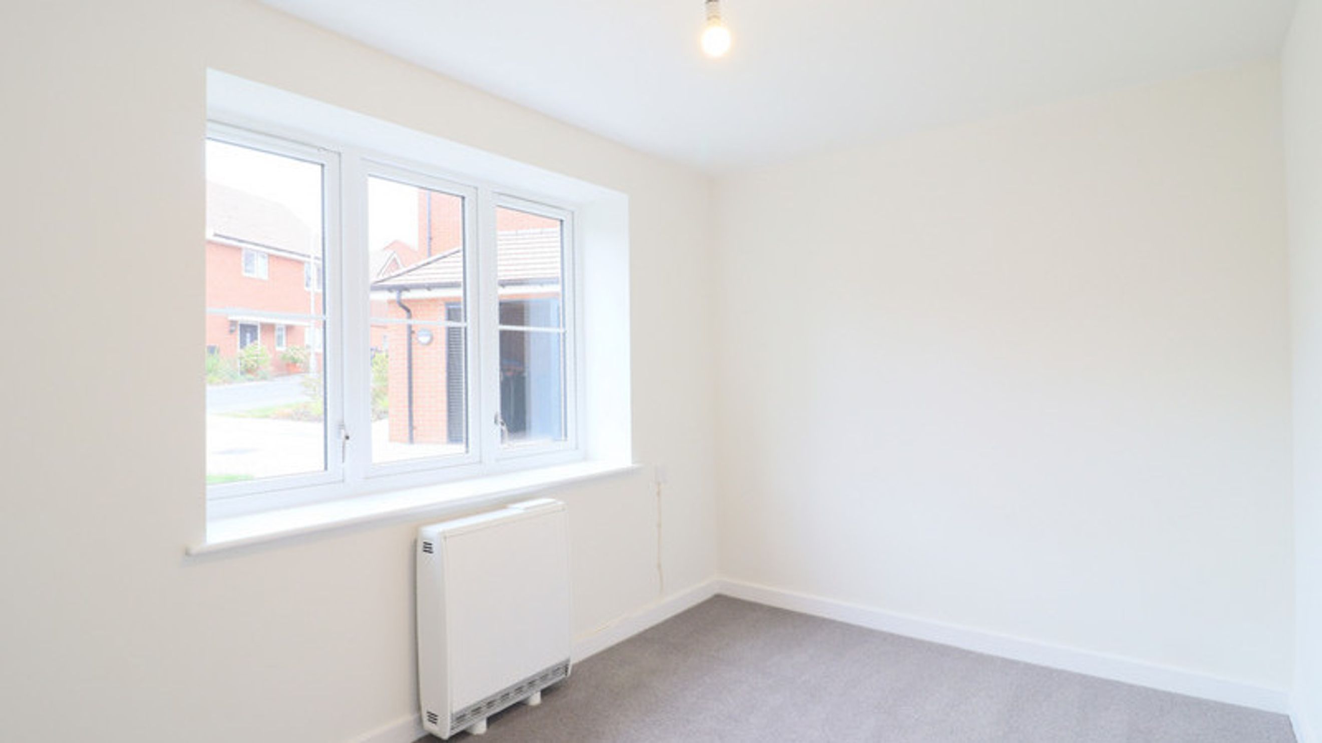 A room with a window, radiator, and carpet.