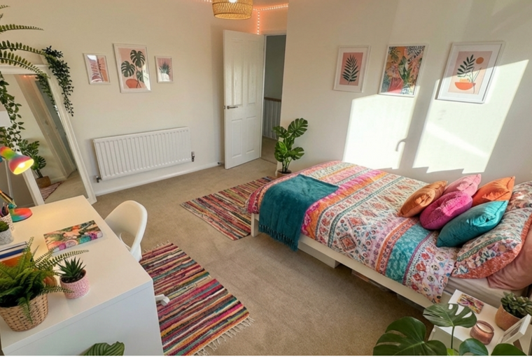 A bedroom with a bed, desk, and multiple rugs.