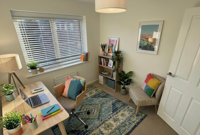 A home office with a desk, chair, bookshelf, and rug.