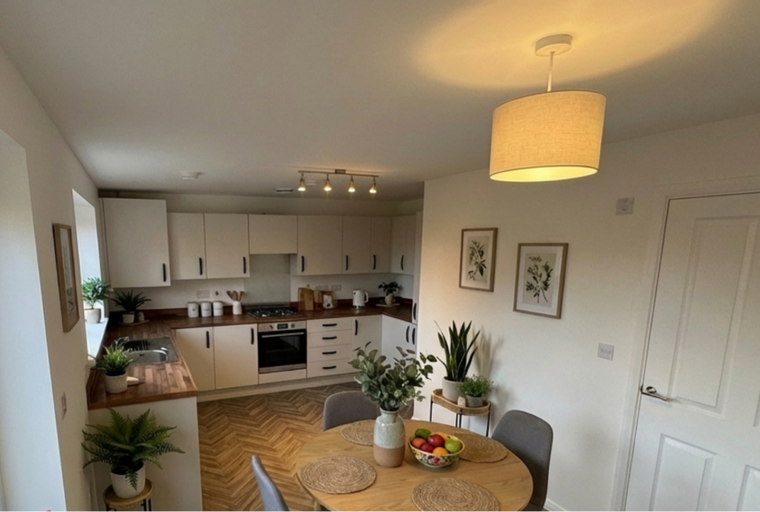 A kitchen and dining area with white cabinets, a wooden countertop, a round table, and two chairs.