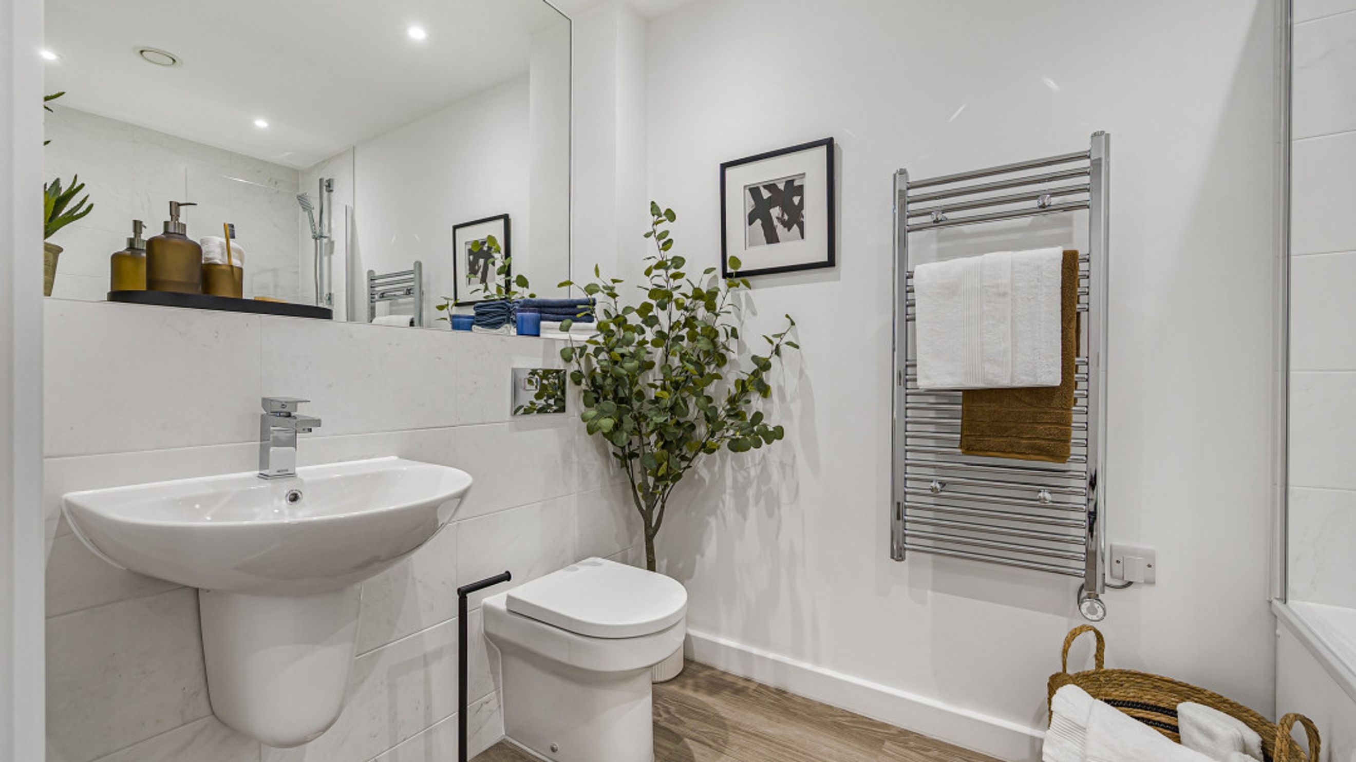 A bathroom with a sink, toilet, and heated towel rack.