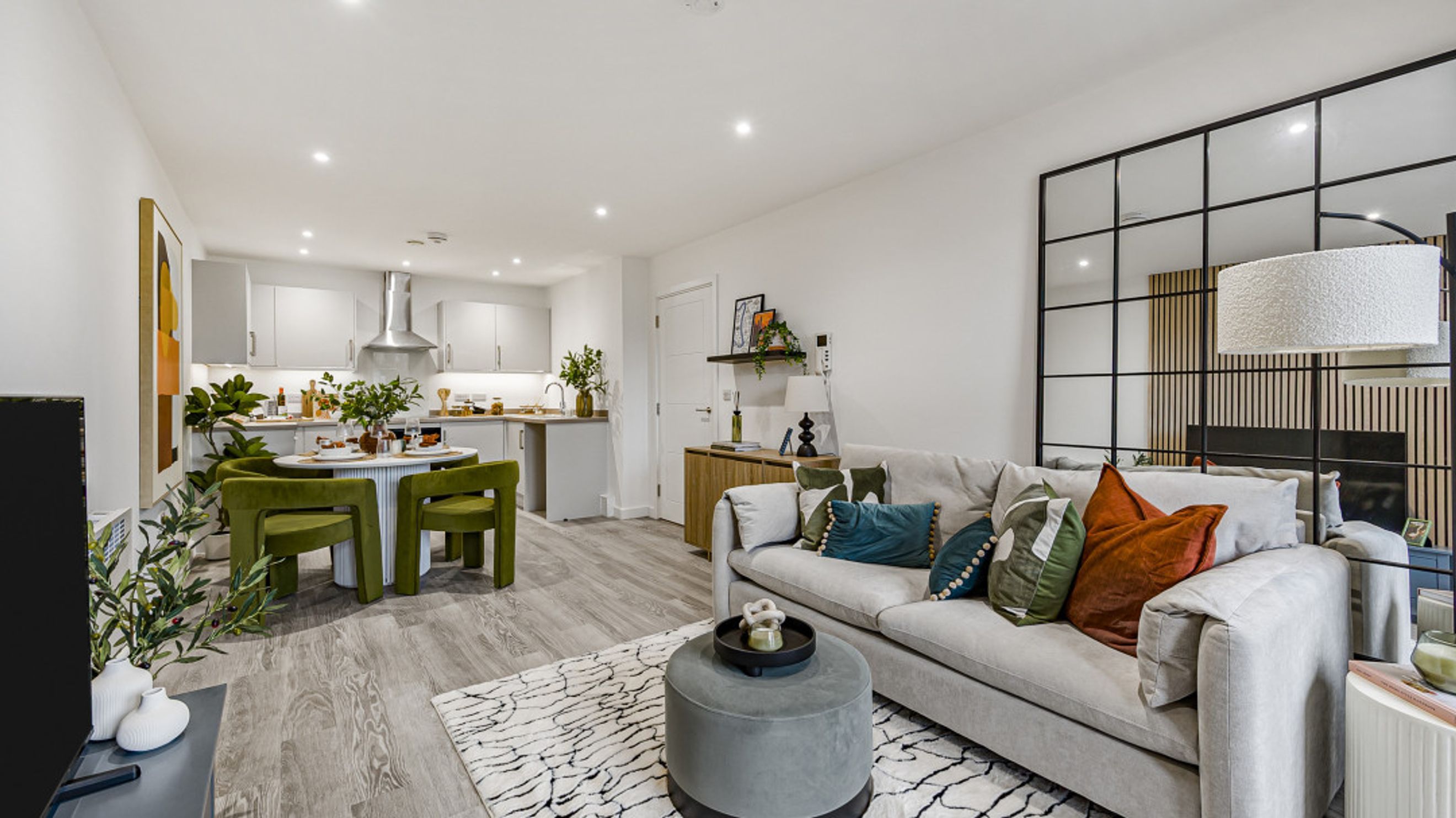 A living room and kitchen area with a sofa, dining table, and kitchen cabinets.