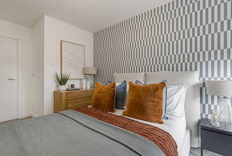 A bedroom with a bed, pillows, nightstands, and a patterned accent wall.