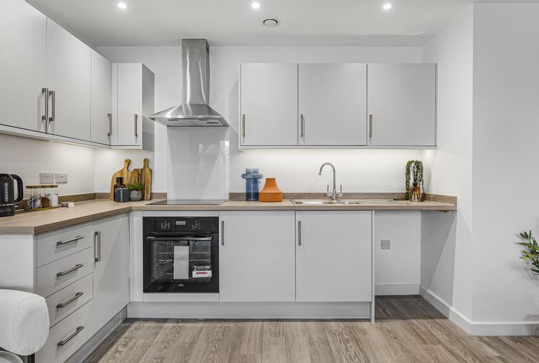 A modern kitchen with white cabinets, a laminate countertop, and a built-in oven.