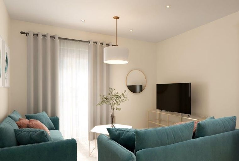 A living room with teal sofas, a coffee table, and a television.