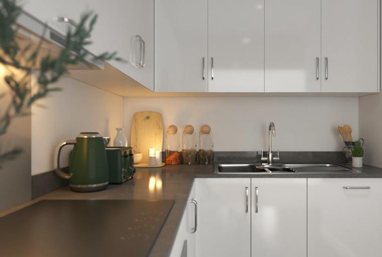 A modern kitchen with white cabinets, a dark countertop, and a stainless steel sink.