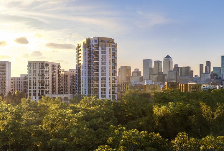 A cityscape with modern apartment buildings and skyscrapers, surrounded by trees.