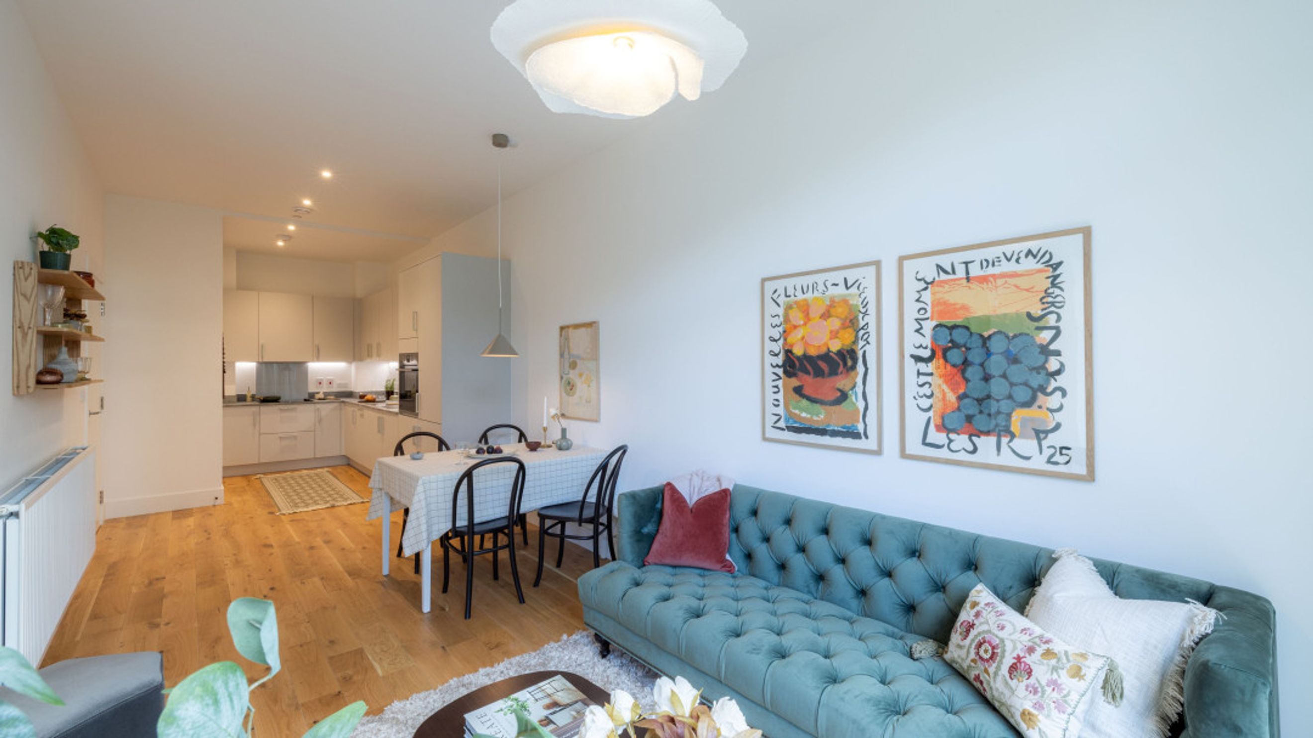 A living and dining area with a sofa, dining table, and kitchen in the background.